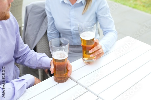 Midsection of business couple holding beer glasses at outdoor restaurant