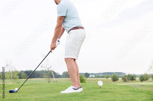 Low section side view of man playing golf against clear sky