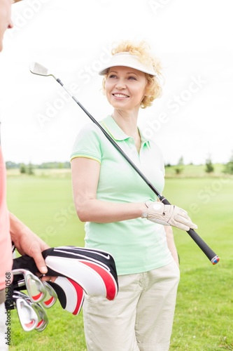 Happy woman looking at male friend at golf course