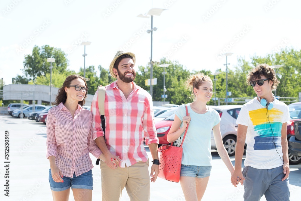 Happy male and female friends walking on city street