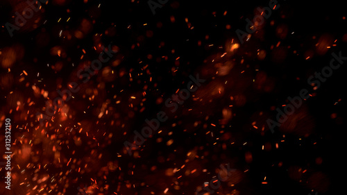Фотография Burning red hot sparks fly from large fire in the night sky