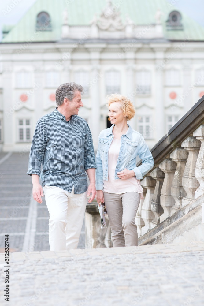 Happy middle-aged couple looking at each other while climbing steps