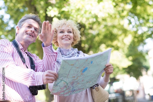 Happy middle-aged couple holding map in city