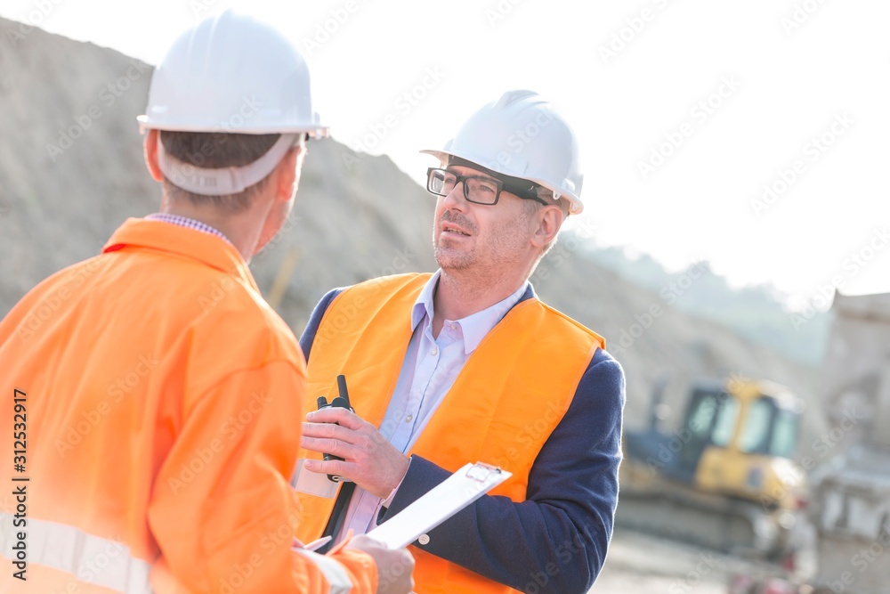 Architects discussing at construction site on sunny day Architects discussing at construction site on sunny day