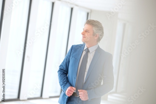 Confident mature businessman looking away in new office
