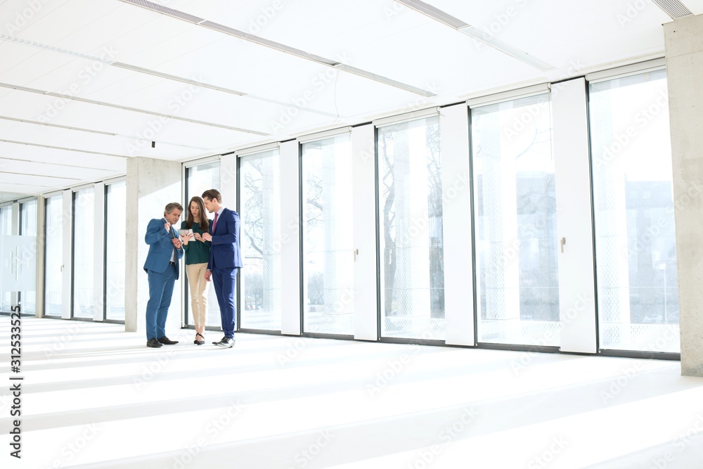 Full length of business people using digital tablet in empty office Full length of business people using digital tablet in empty office