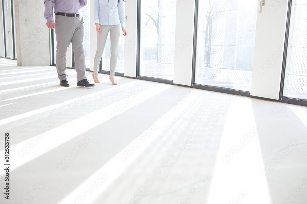 Low section of business people walking by windows in empty office