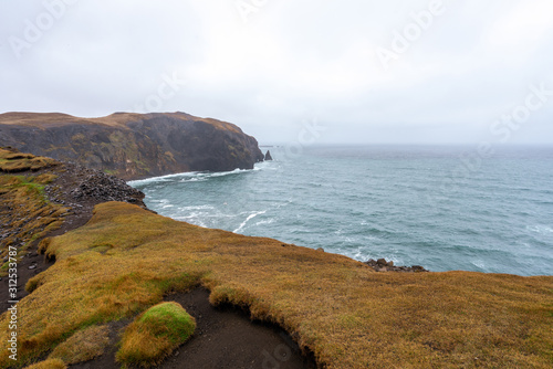 Ketubjorg steep cliffs and basalt sea stacks in the skagi peninsula in the northern part of Iceland. Waves crash ashore during rainy and stormy weather. Traveling and Icelandic concept. photo