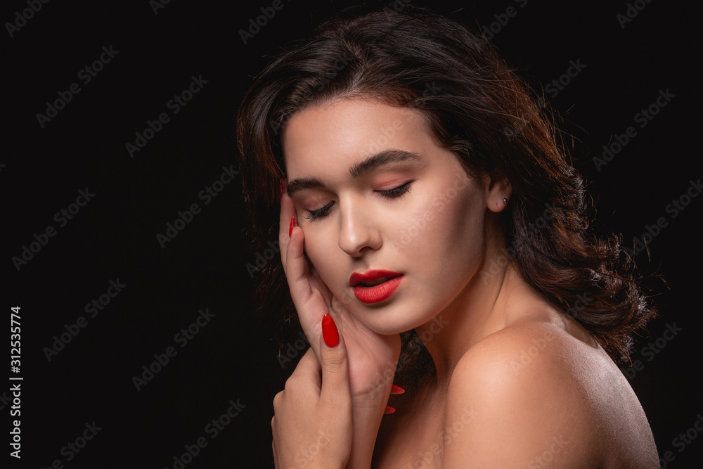 Beautiful woman with bright makeup posing isolated over black background.