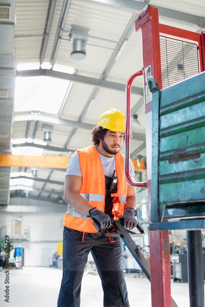 Young male worker pushing hand truck in metal industry Young male worker pushing hand truck in metal industry
