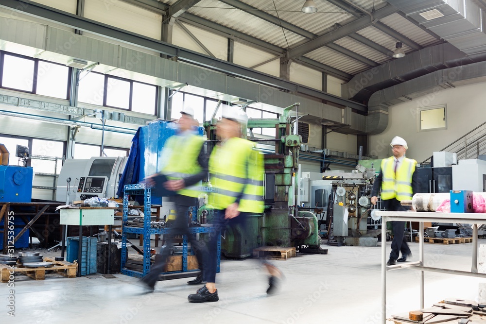 Fototapeta premium Blurred motion of business people wearing reflective clothing walking in metal industry
