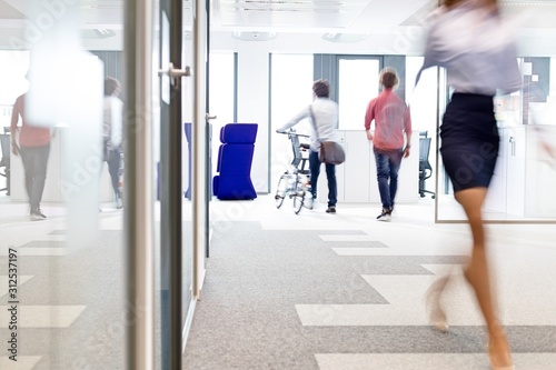 Blurred motion of businesswoman walking with male colleagues in background at office