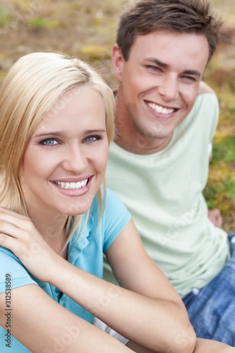 Portrait of smiling young woman with man relaxing in park