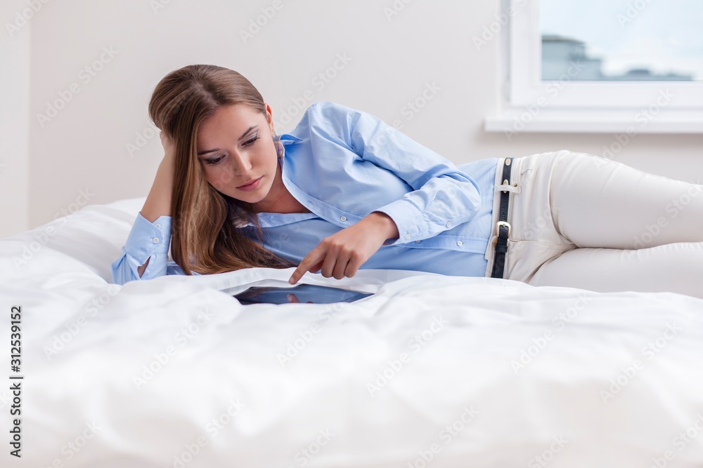 Beautiful woman using tablet computer on her bed