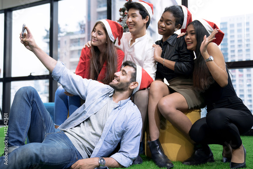 Celebrating New Year together, group of beautiful young people in Santa hats having fun.