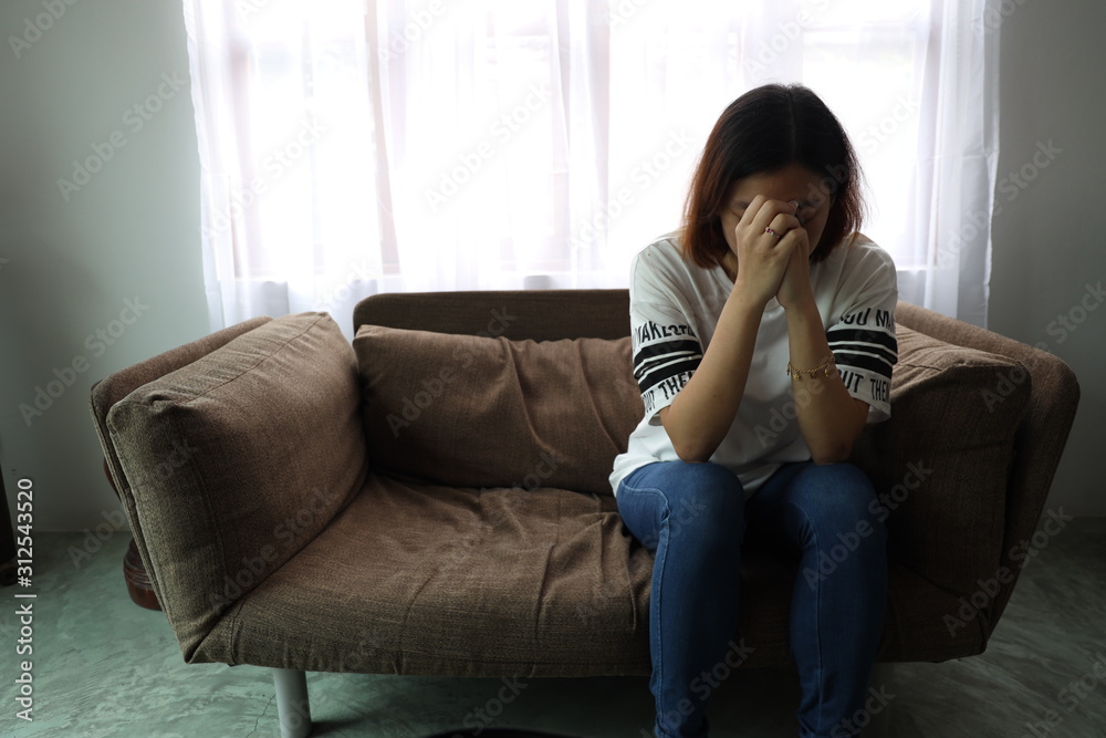 Asian woman stressful face with her hands cover of face. Short hair asian Woman feel lonely and sad sit alone on sofa bed in the living room Asian woman stressful face with her hands cover of face. Short hair asian Woman feel lonely and sad sit alone on sofa bed in the living room