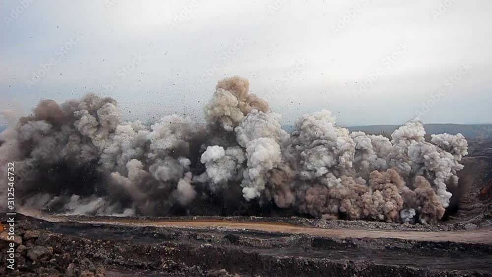 Explosion of rock with coal for mining. The camera shakes from the huge vibration of the earth. Stones fly up and into the camera