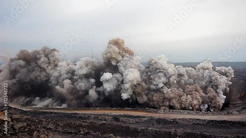 Explosion of rock with coal for mining. The camera shakes from the huge vibration of the earth. Stones fly up and into the camera photo