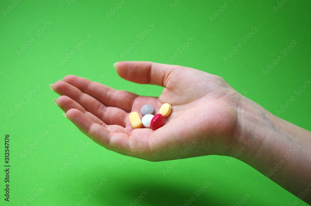 Hand holding colored pills capsules on green background. Healthy lifestyle and pharmacy industry concept. Hand holding colored pills capsules on green background. Healthy lifestyle and pharmacy industry concept.