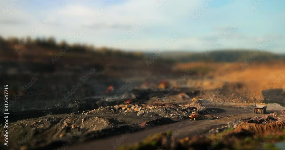 Timelapse tilt-shift panorama of coal mining quarries, red excavators dig coal and load into yellow dump trucks