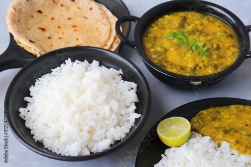 Assorted Indian food for lunch or dinner, rice, spinach lentils/Palak dal, Roti or naan, Alu Vadi and surnache kap / Yam fry. selective focus with Copy space photo