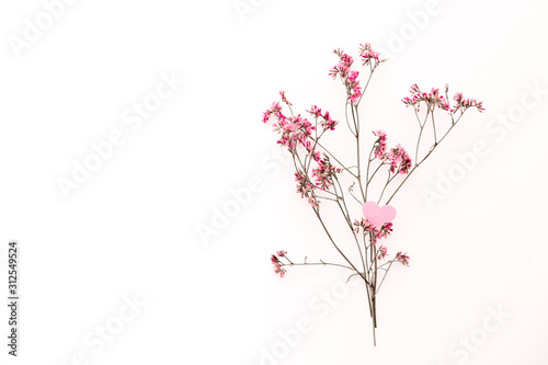 A small pink heart with a place for text decorated with branch of flowers on a white background