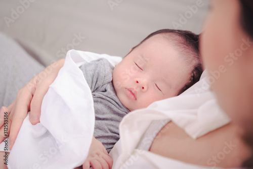Asian woman holding a newborn baby in her arms at home.Mother day and newborn baby infant health care concept.