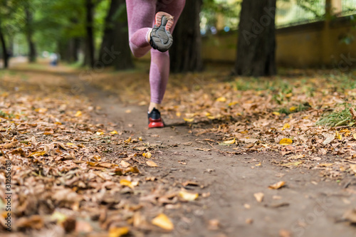 Close up of feet of runner running in autumn leaves training exercise