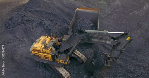 Aerial view from drone excavator loads coal into a dump truck