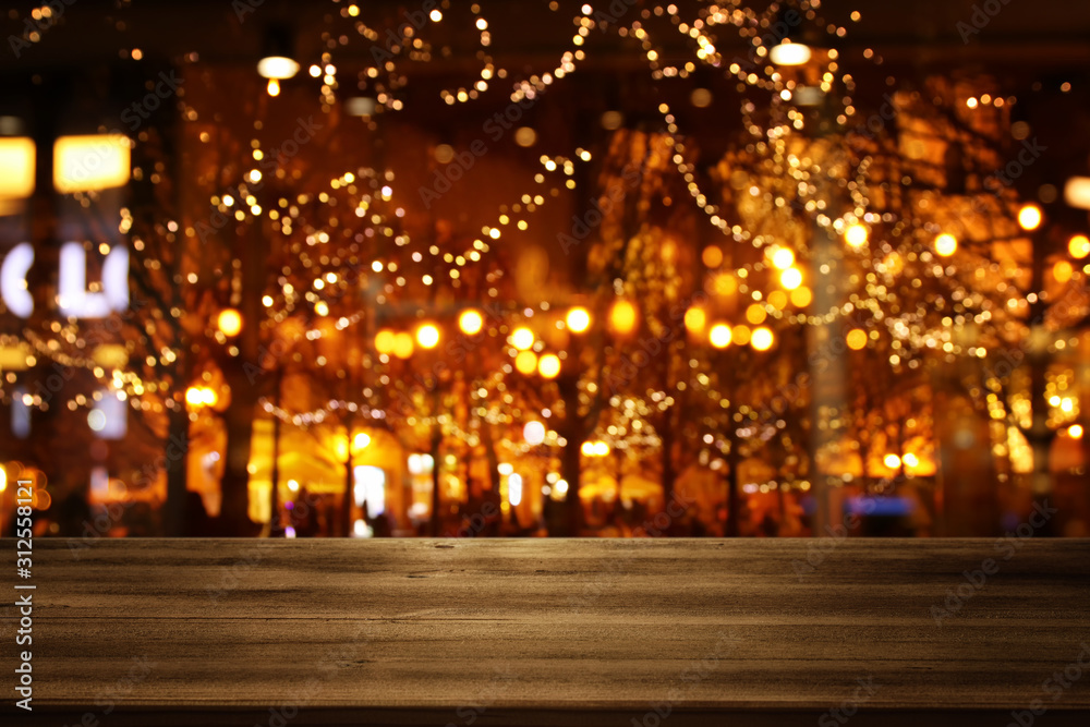 background Image of wooden table in front of street view in front of abstract blurred lights background Image of wooden table in front of street view in front of abstract blurred lights
