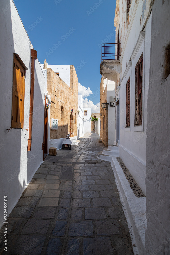 Narrow lane with white houses in Lindos on Greek island Rhodes
