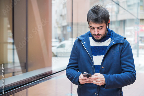 Handsome young man, walking in city street using mobile phone .