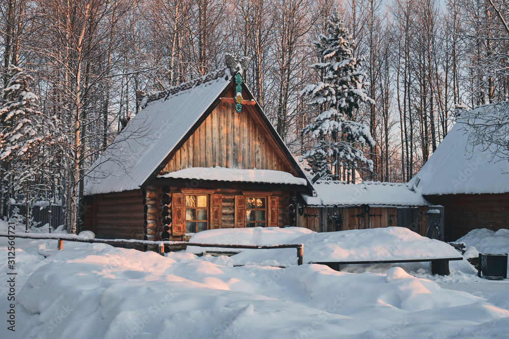 Wooden house in winter forest. Snow-covered birch and spruce trees in the background.