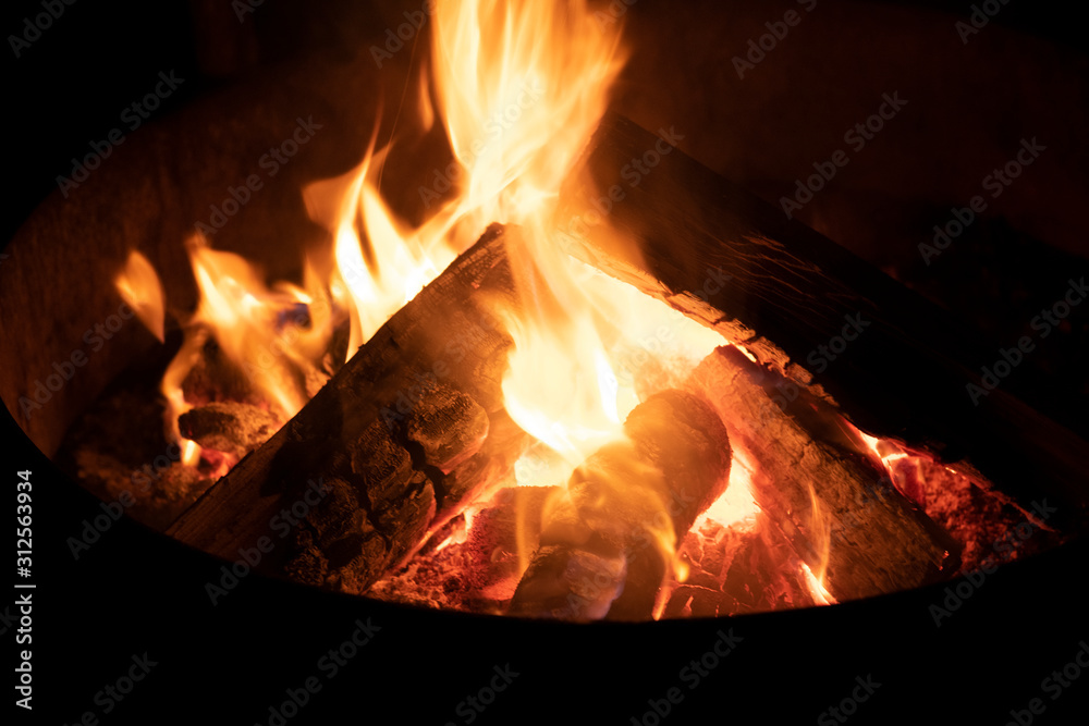 Fototapeta premium A glowing camp fire providing comfort and light during a cool summer night in a national park.