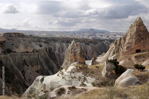 The general view of valley in Cappadocia mountains with Uchisar city on background. Day is cloudly, but sunny.