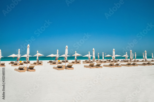 Vacation holidays beach background. The beach with sunbeds and sunshades in Dubai, on the shores of the Arabian Gulf. © sablinstanislav