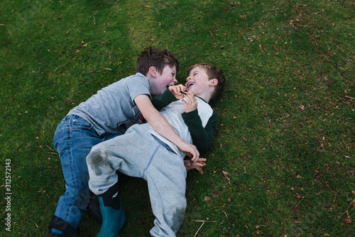 Siblings playing wrestle outside on the grass. photo