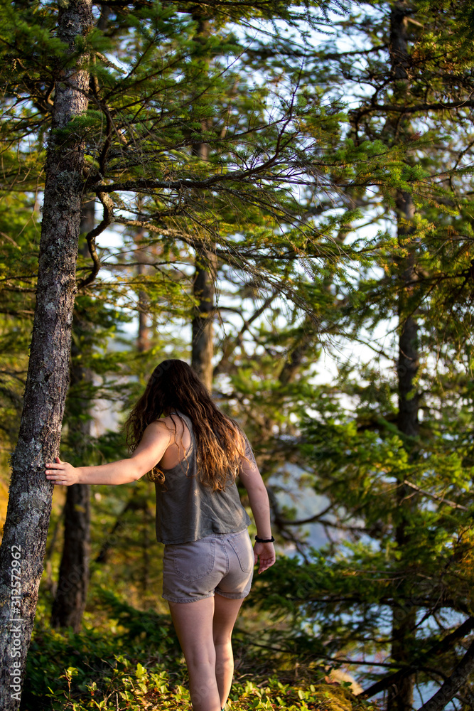 A fit young woman walking through the forest at sunset A fit young woman walking through the forest at sunset