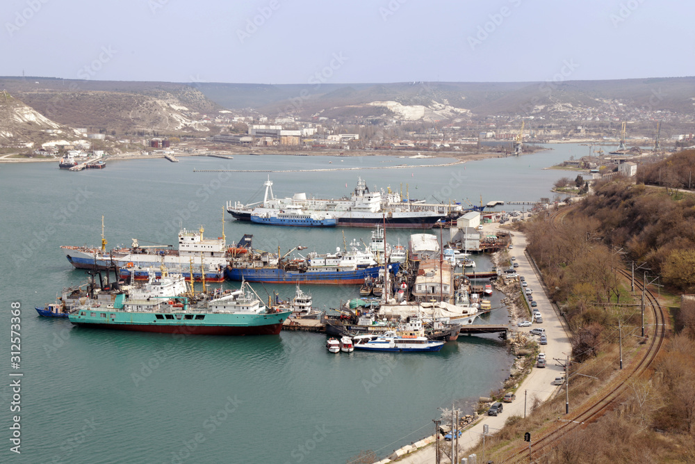 Top view on beginning of Sevastopol bay with many ships and docks. Railway is at right of picture. Day is sunny.