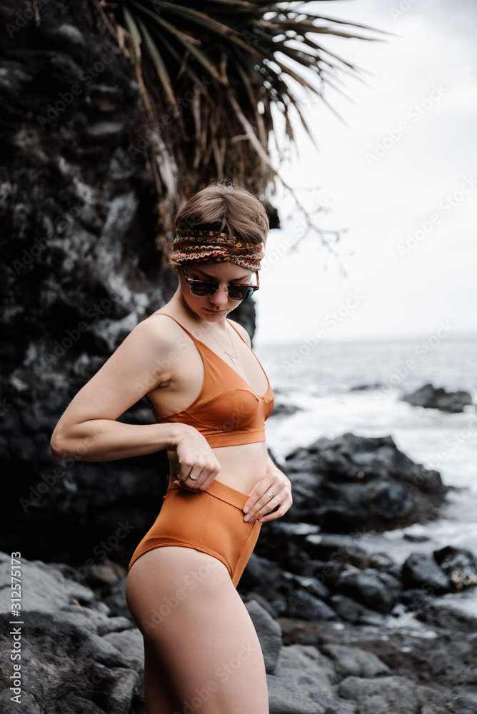 Young happy woman standing on rock beach Young happy woman standing on rock beach