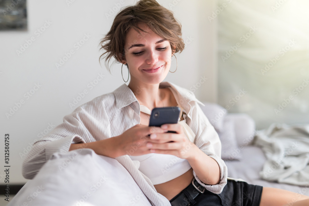 Pretty young girl using her smartphone on couch at home in the living room Pretty young girl using her smartphone on couch at home in the living room