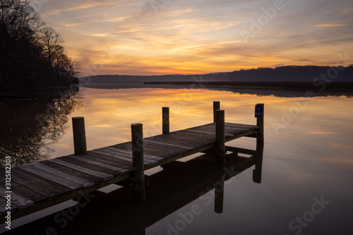 Dock at Sunrise on a Calm Morning with Orange Sky and Reflections