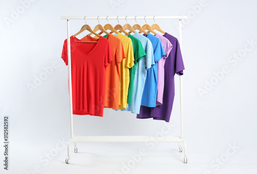 Colorful clothes hanging on rack against white background