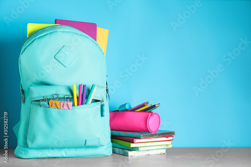 Stylish backpack with different school stationery on table against light blue background. Space for text © New Africa