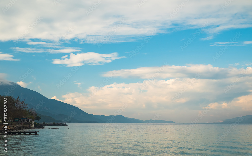 Seascape in cloudy weather. Silhouette of blue sky and mountains in background