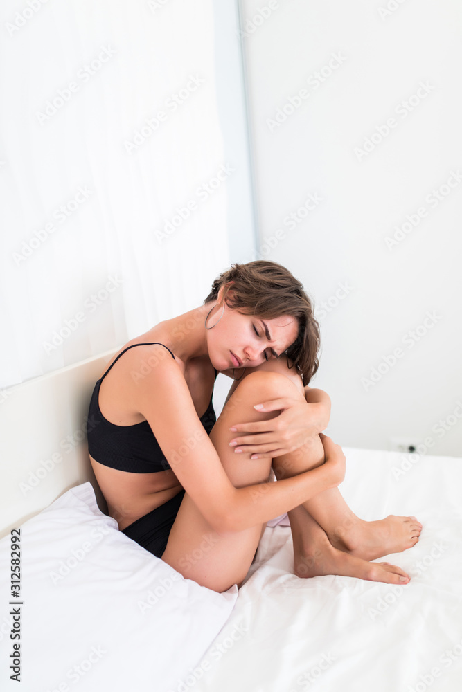 Sad woman in black underwear sitting on the bed at the morning Sad woman in black underwear sitting on the bed at the morning