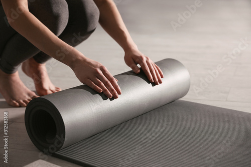 Obraz na plátně Woman rolling yoga mat in studio, closeup