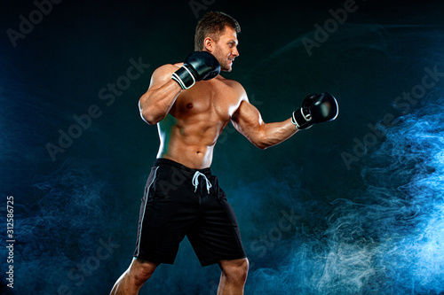 Fitness and boxing concept. Boxer, man fighting or posing in gloves on dark background. Individual sports recreation. © Mike Orlov
