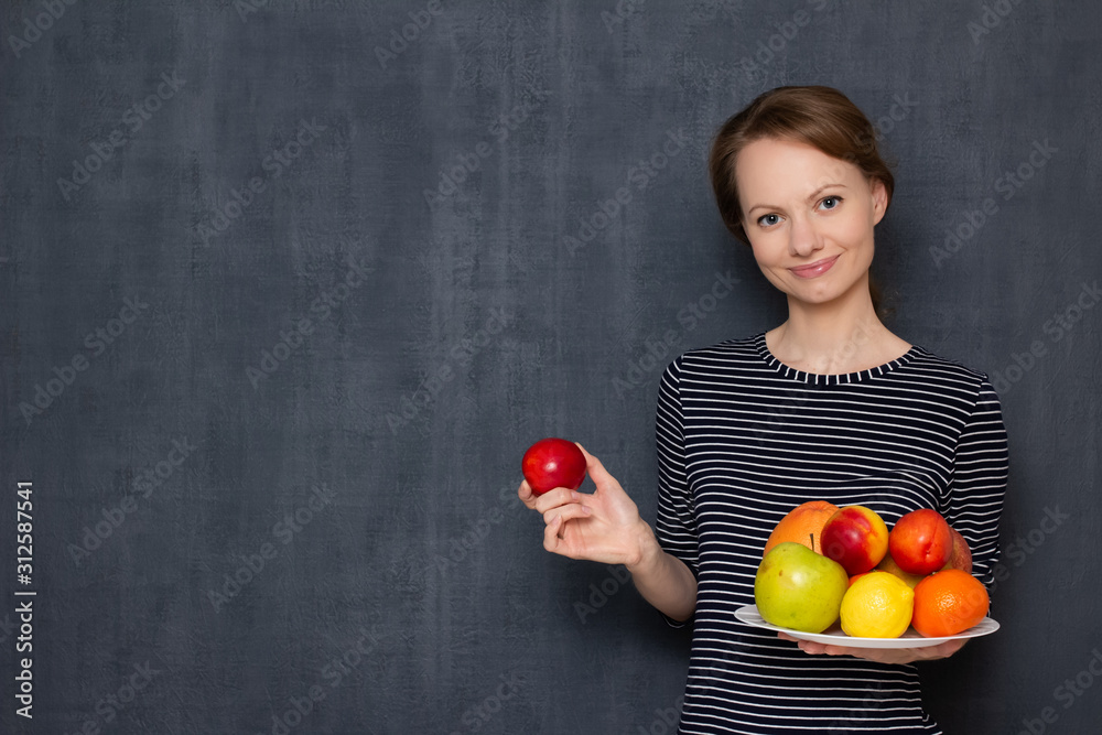 Portrait of happy young woman smiling and holding plate of fruits Portrait of happy young woman smiling and holding plate of fruits