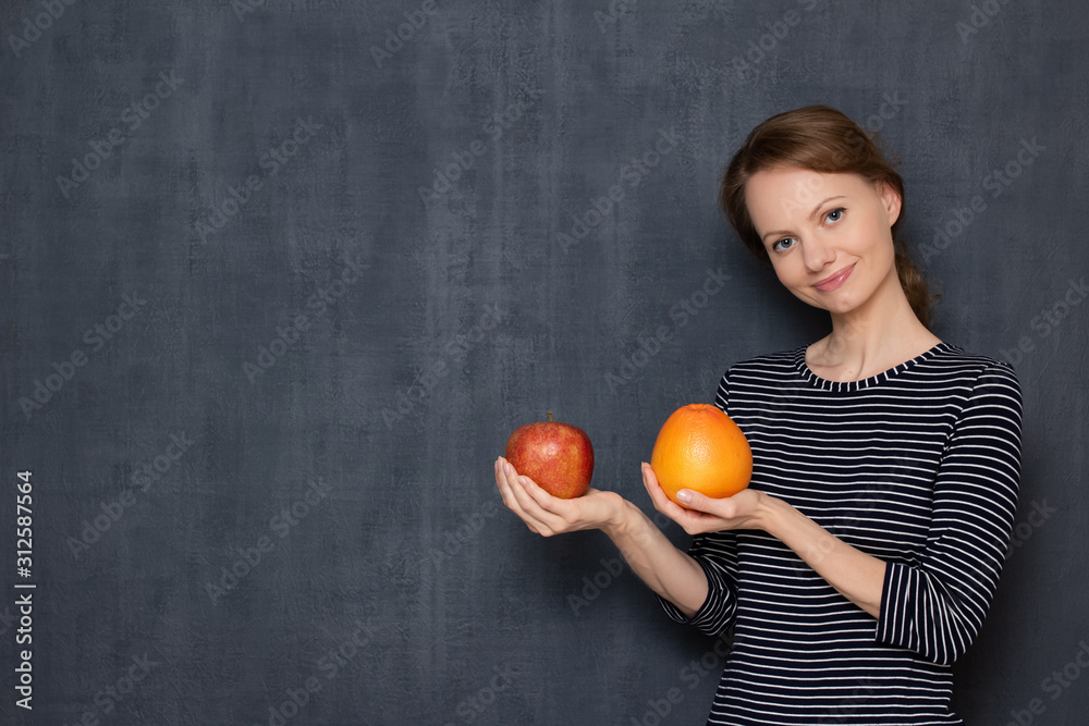 Portrait of happy pretty girl smiling and holding grapefruit and apple Portrait of happy pretty girl smiling and holding grapefruit and apple